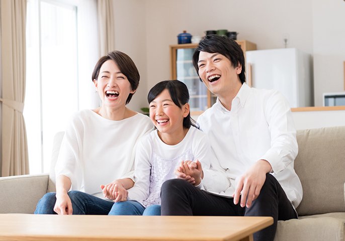 テレビを見る両親と娘の写真