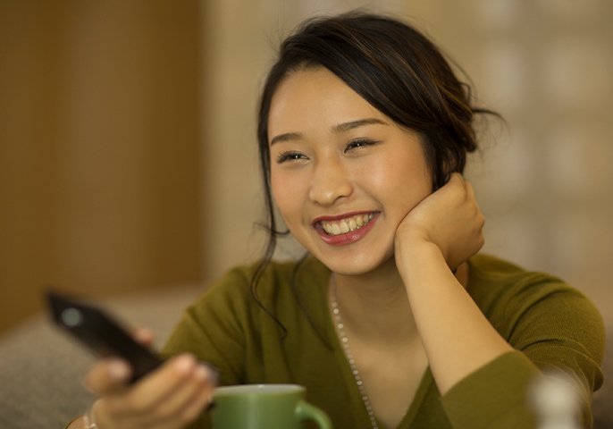 楽しそうにテレビを見る女性の写真
