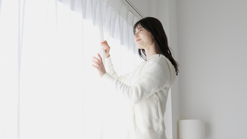 女性がカーテンを開けるイメージ