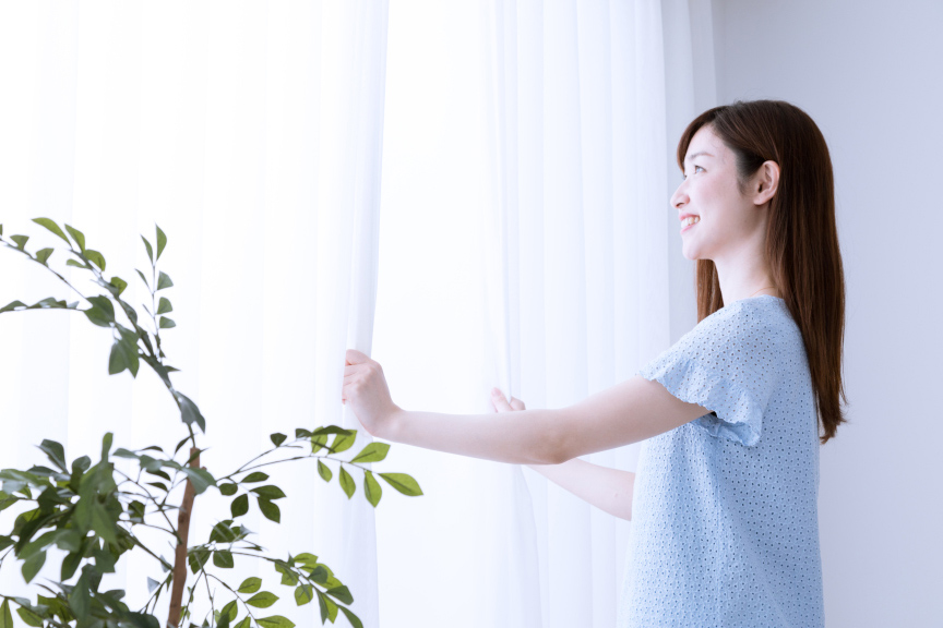 写真：女性がカーテンを開けているイメージ