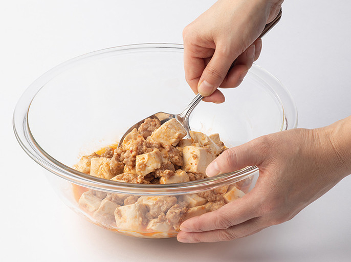 ボウルに入れた麻婆豆腐をスプーンでかき混ぜているイメージの写真
