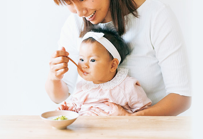 写真:母親が子どもに離乳食を食べさせているイメージ