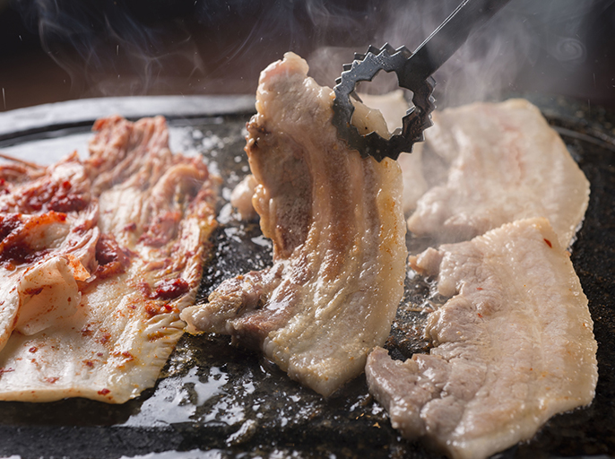 写真:鉄板で豚肉とキムチを焼いているイメージ