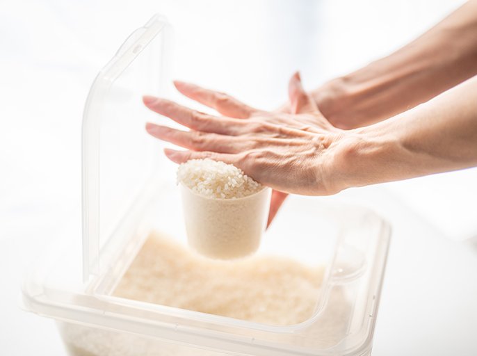 写真：計量カップにすくったお米を手ですりきるイメージ