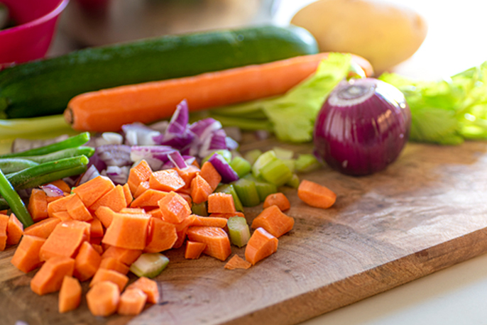 写真：まな板の上に並ぶ数種類の野菜。一部はカット済み