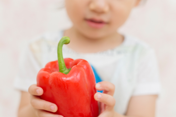 写真：赤いパプリカを持つこども