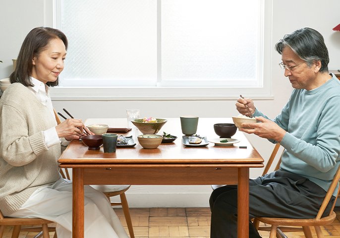 写真：中年夫婦が食卓を囲んで食事しているイメージ