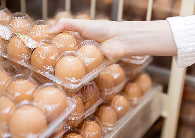 写真：売り出されている卵パックをとろうとしているイメージ