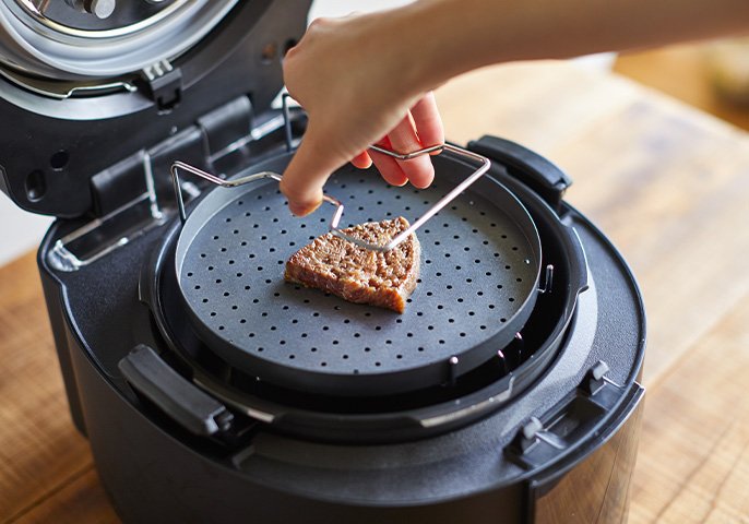 写真：お肉が置かれた専用皿をデリソフターにセットしてるイメージ