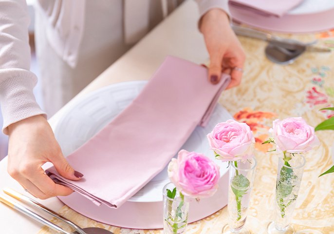 写真：ピンクのテーブルクロスを持つ手元のイメージ