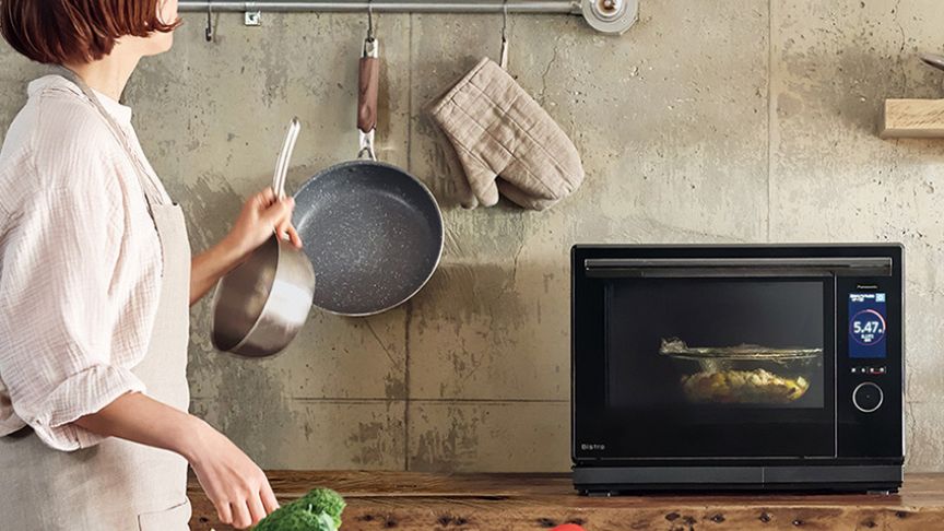 キッチンで料理をする女性とオーブンレンジの写真