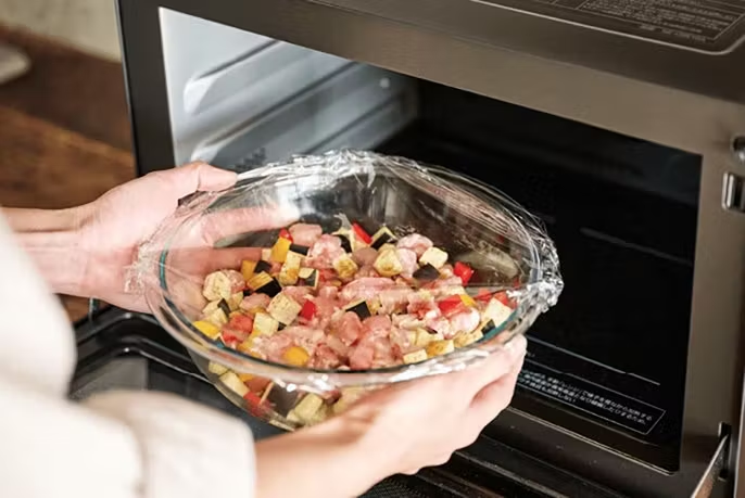写真：オーブンレンジに食材を入れているイメージ