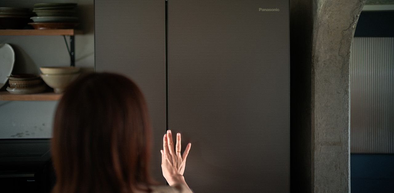 冷蔵庫に手を伸ばしている女性の写真