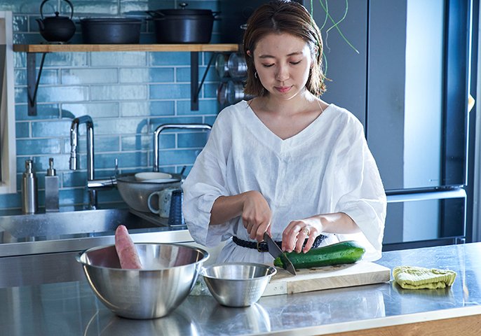 女性がキッチンで野菜を切っている様子