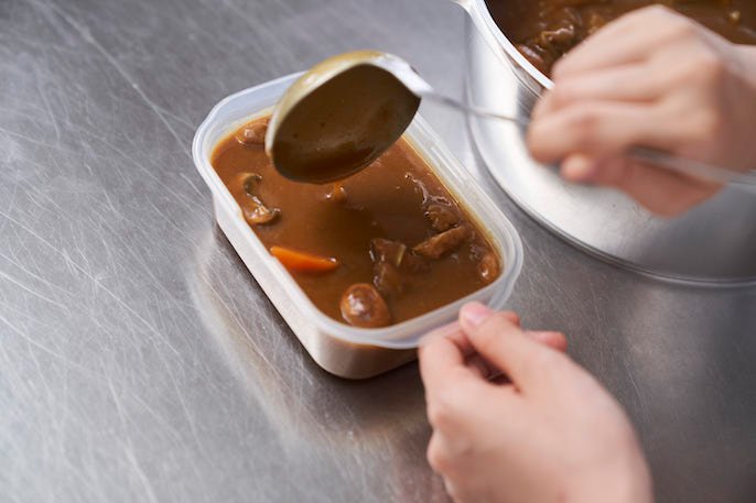 保存容器にカレーを入れている様子の写真
