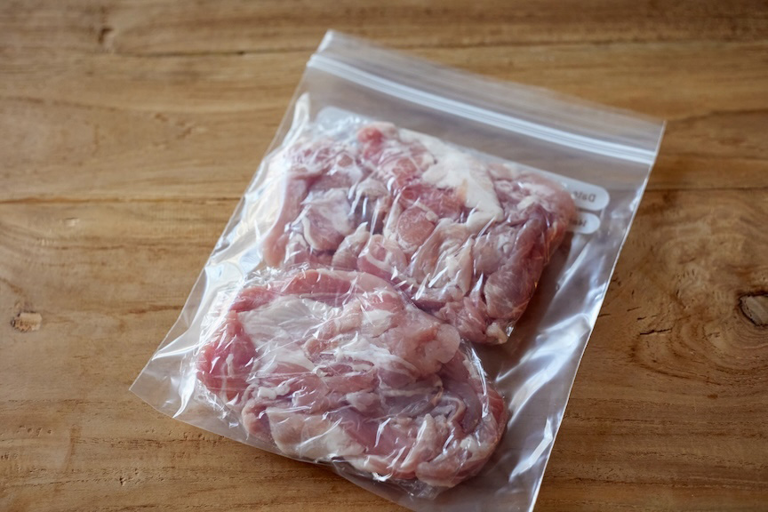 小分けにした肉を薄く平らになるように広げてラップで包み、冷凍用保存袋に入れた様子の写真