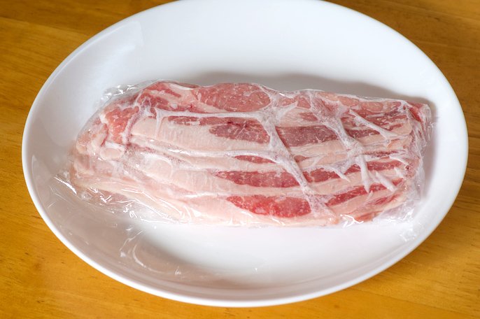 写真：ラップで包まれた豚肉がお皿の上に置かれた様子