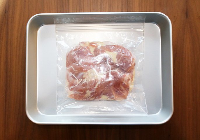 写真：肉が入っている冷凍用保存袋が、金属製のトレーの上に置かれた様子