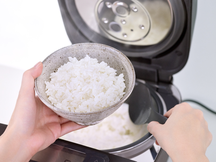 写真：炊飯器から炊き上がった白ご飯をしゃもじで茶碗によそう様子