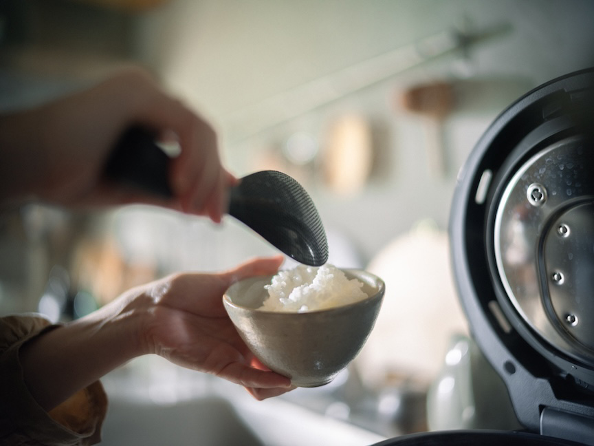 写真：炊飯器から茶碗にご飯をよそう様子