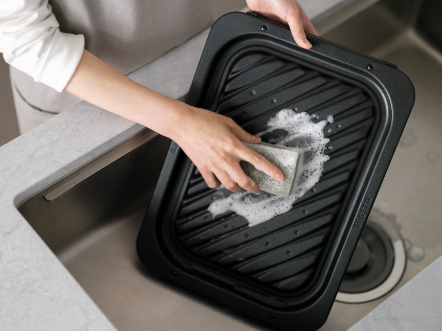 シンクでトレーを洗っている人の写真