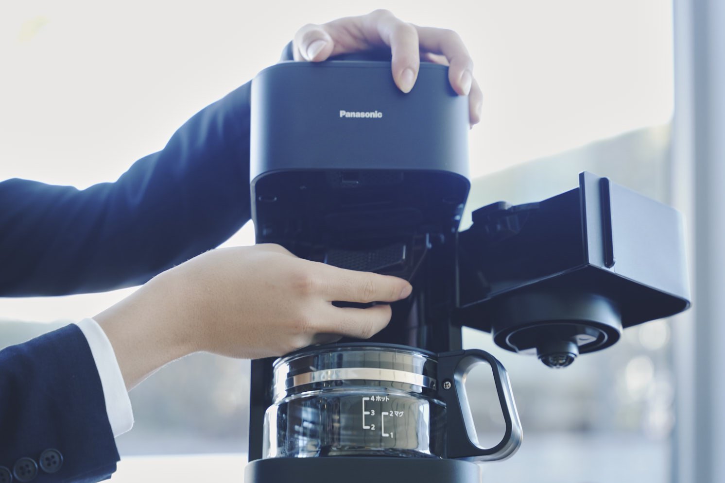 コーヒーメーカーの縦型ミルの部分に手をかけている写真