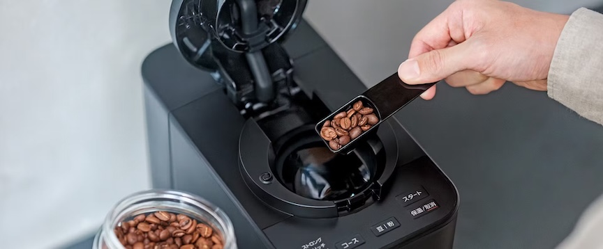 コーヒーメーカーにコーヒー豆を入れている写真