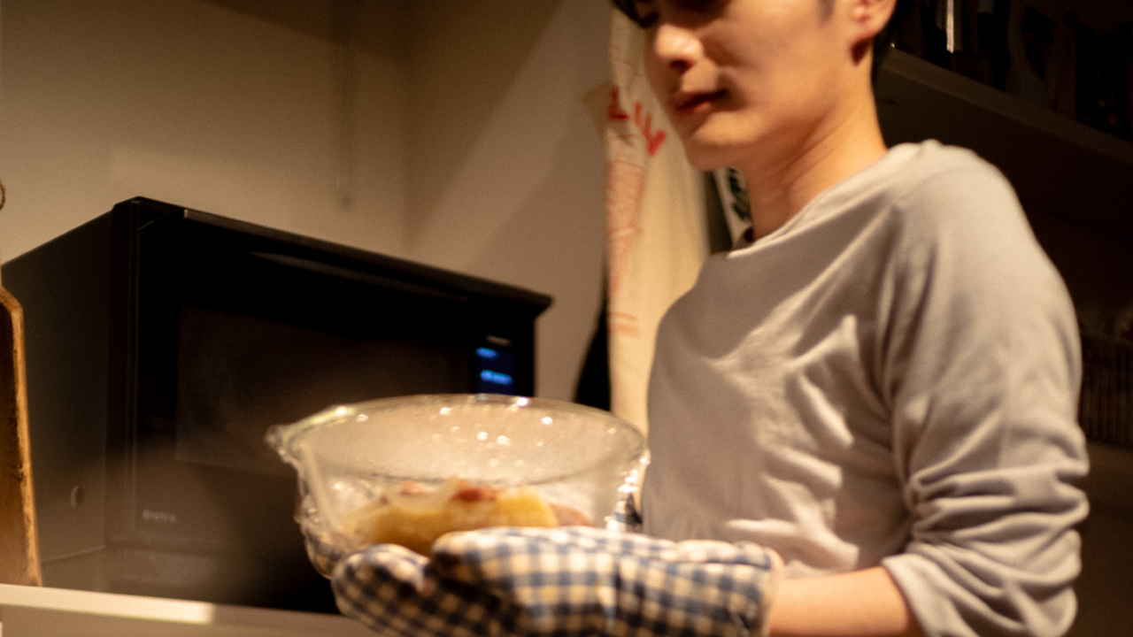 電子レンジから料理を取り出している様子の写真