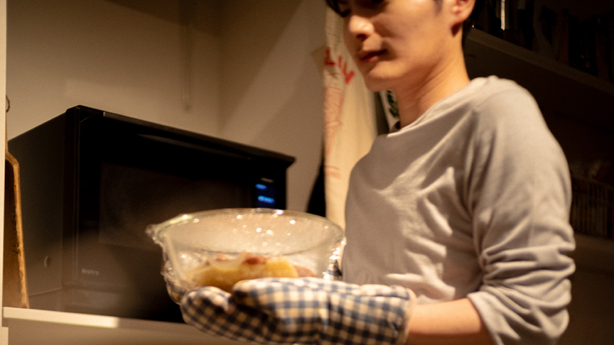 電子レンジから料理を取り出している様子の写真