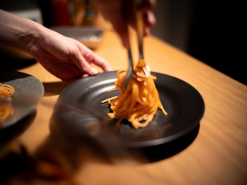 お皿にパスタを盛り付ける様子の写真