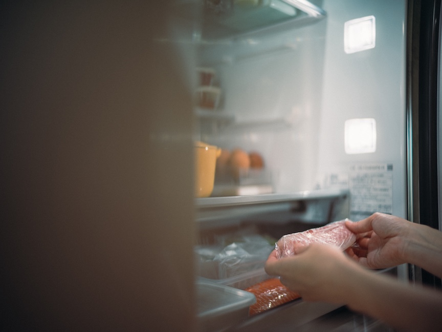冷蔵庫からラップに包んだ食品を取り出す様子の写真