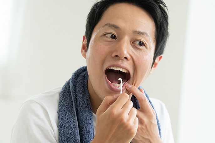 写真：糸ようじを使って歯間をみがく男性