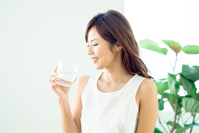写真：グラスに入った水を飲もうとしている女性