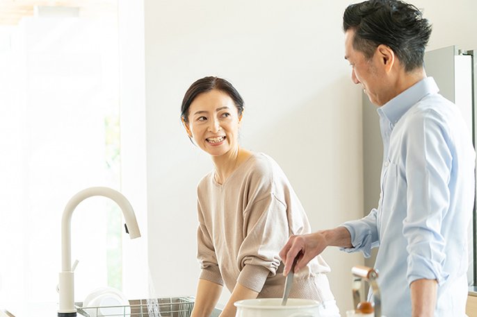 写真：台所で中年夫婦が笑顔で会話しているイメージ