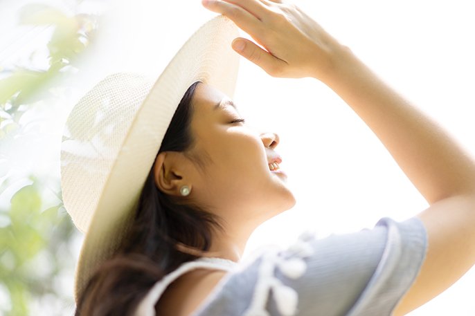 写真：白い帽子をかぶった女性が空をあおいでいるイメージ