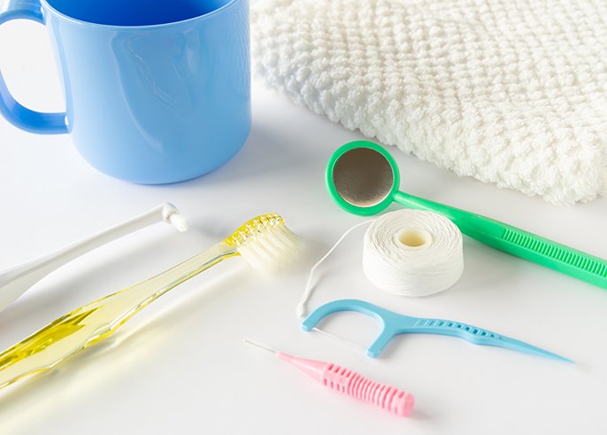 写真：歯ブラシ、糸ようじ、コップ、タオルなどが並んでいるイメージ