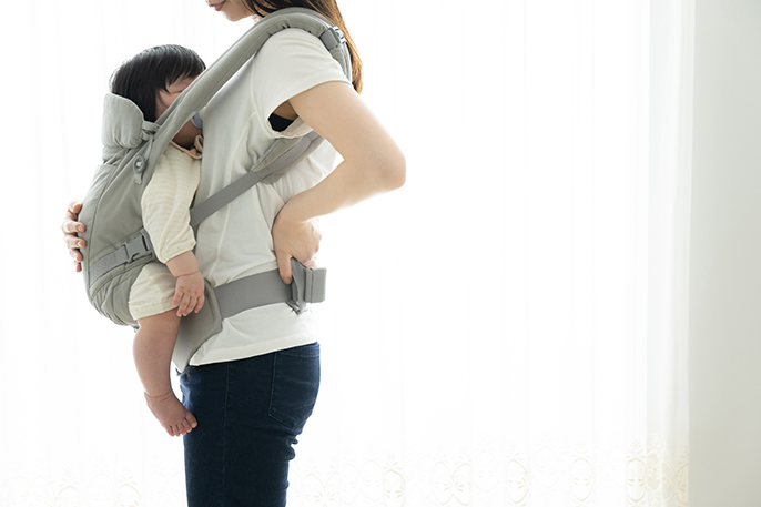 写真：赤ちゃんを抱っこした女性が腰に手を当てている様子