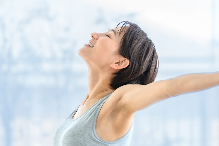 写真：室内で両腕を大きく広げ、深呼吸をしながらストレッチをしている様子。