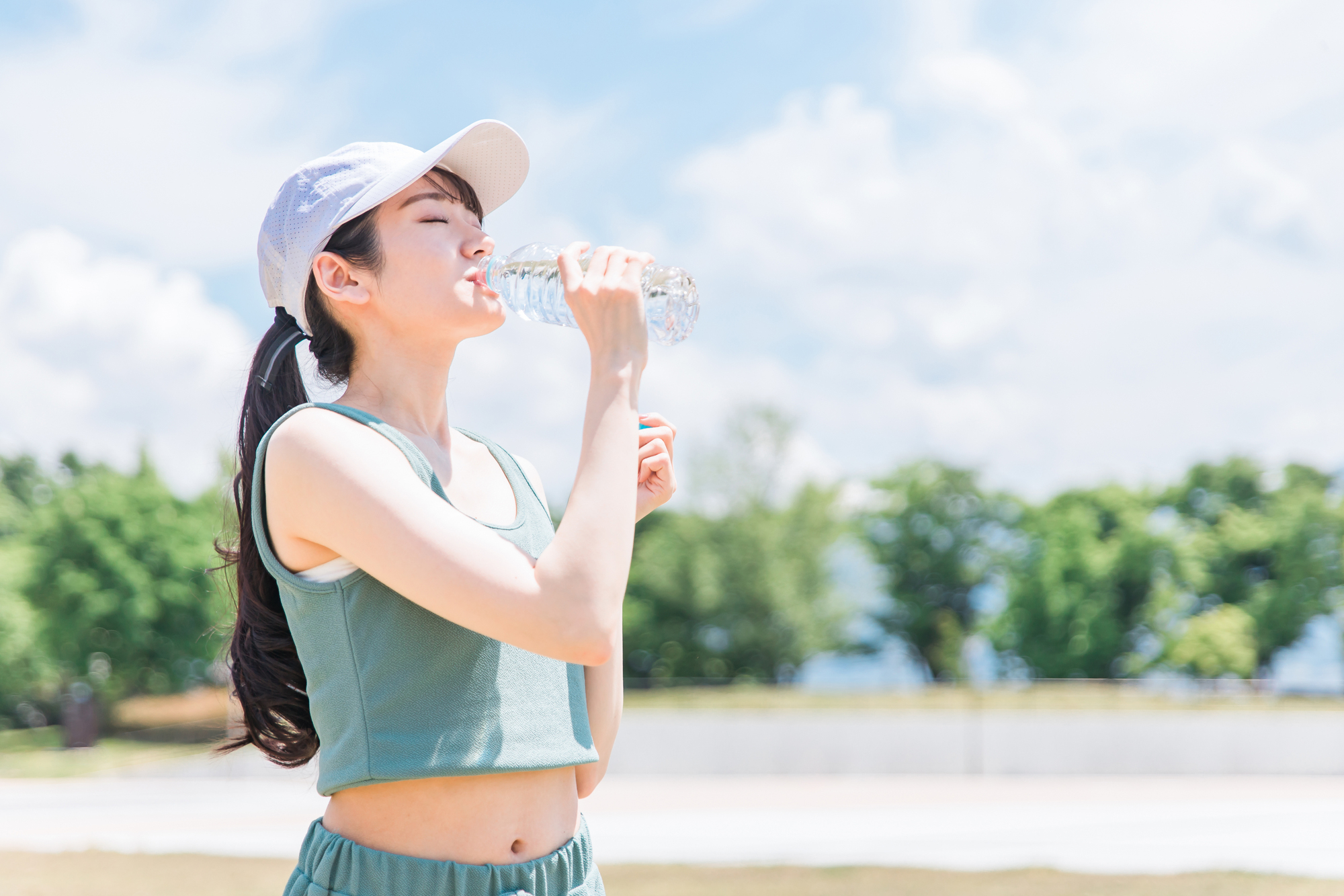 屋外で水分補給をしている女性の写真