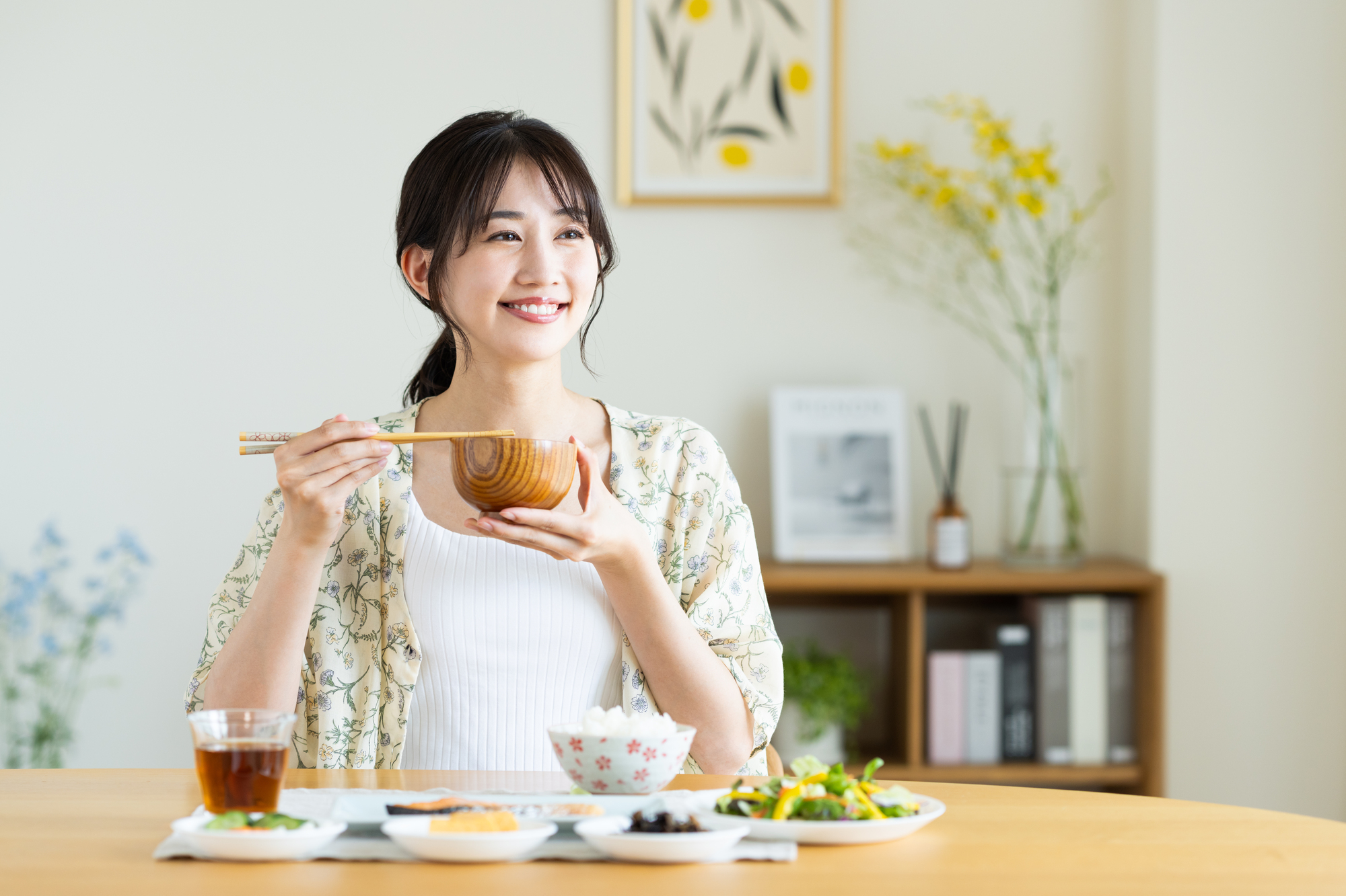 朝食で味噌汁を飲む女性