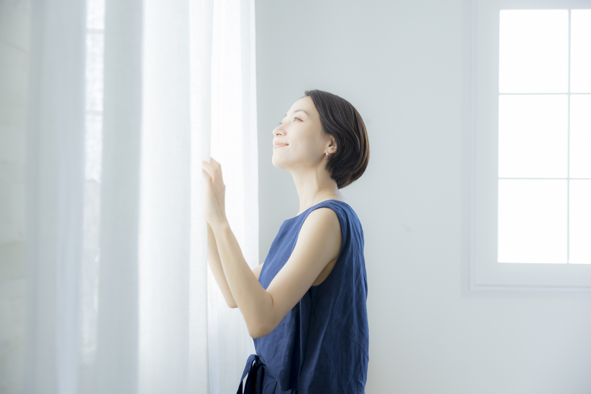 窓の外の日差しを確認する女性