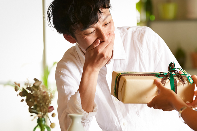 写真：男性がプレゼントを見て驚いている様子