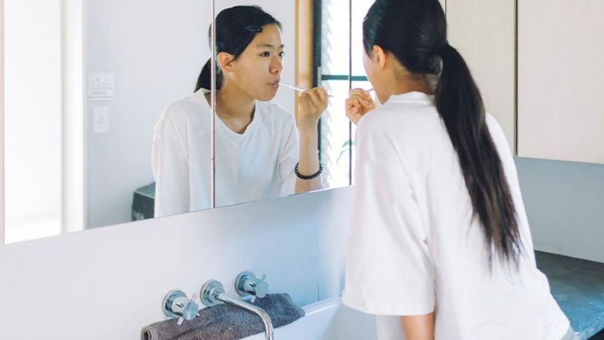 洗面台で歯を磨いている女性の写真