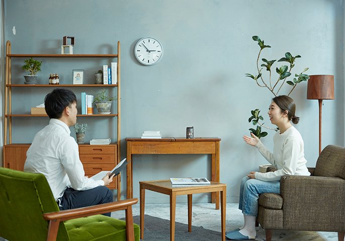 写真：男性と女性が部屋で向かい合って会話しているイメージ