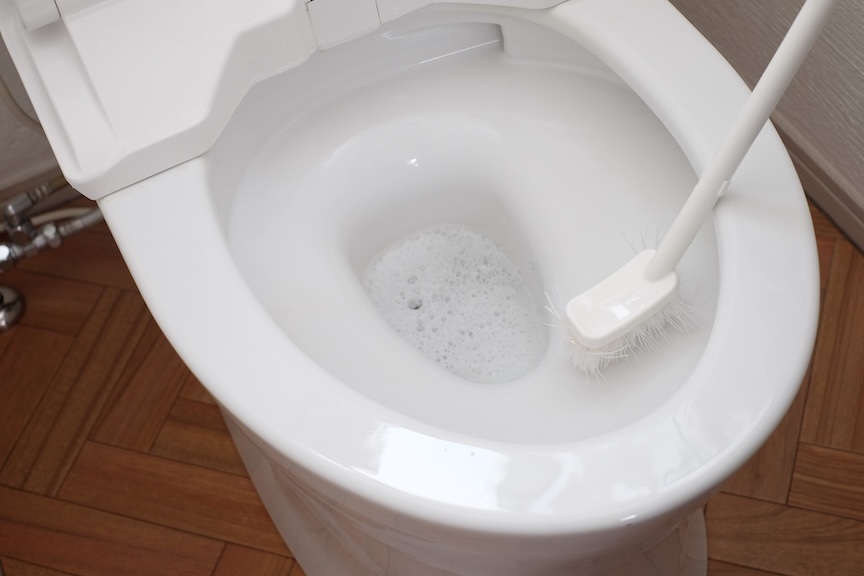 便器の内側をトイレブラシで掃除している写真