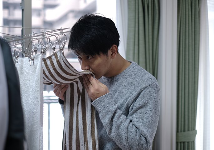 写真：男性が部屋干ししている洗濯物の匂いを嗅いでるイメージ