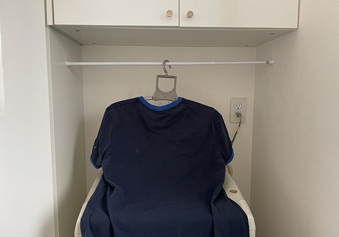 写真：洗濯槽の上に突っ張り棒を設置してハンガーで洗濯物を干しているイメージ