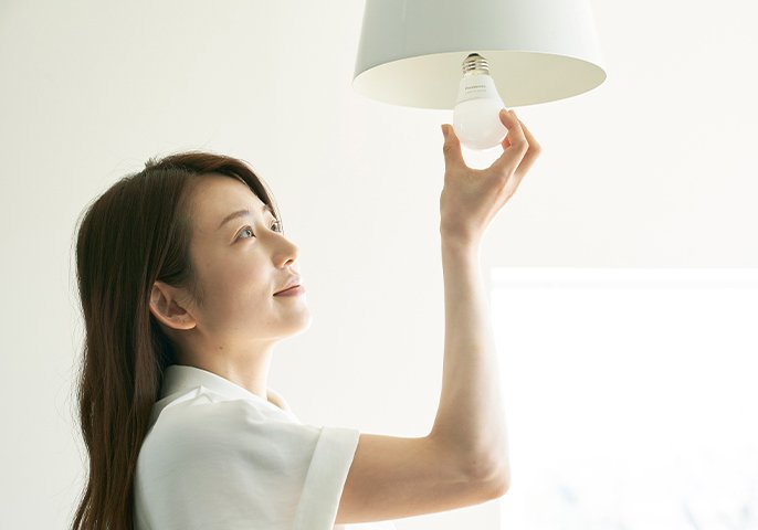 写真：女性が電球を取り替え用としているイメージ