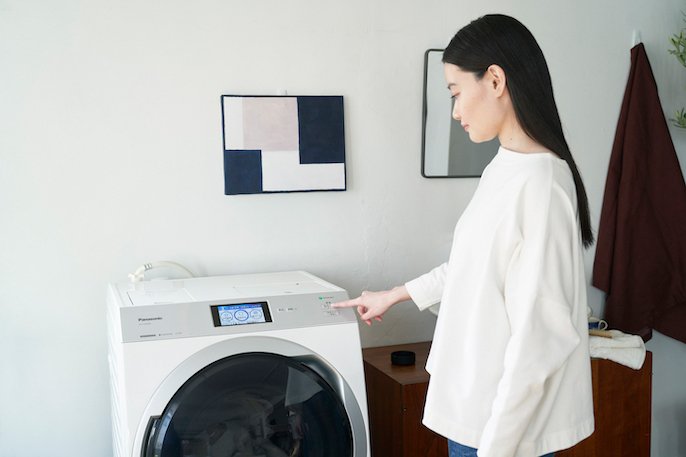 写真：女性が洗濯機を操作している様子
