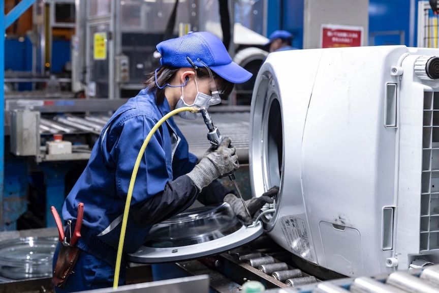 作業着姿の女性が何かを組み立てている写真